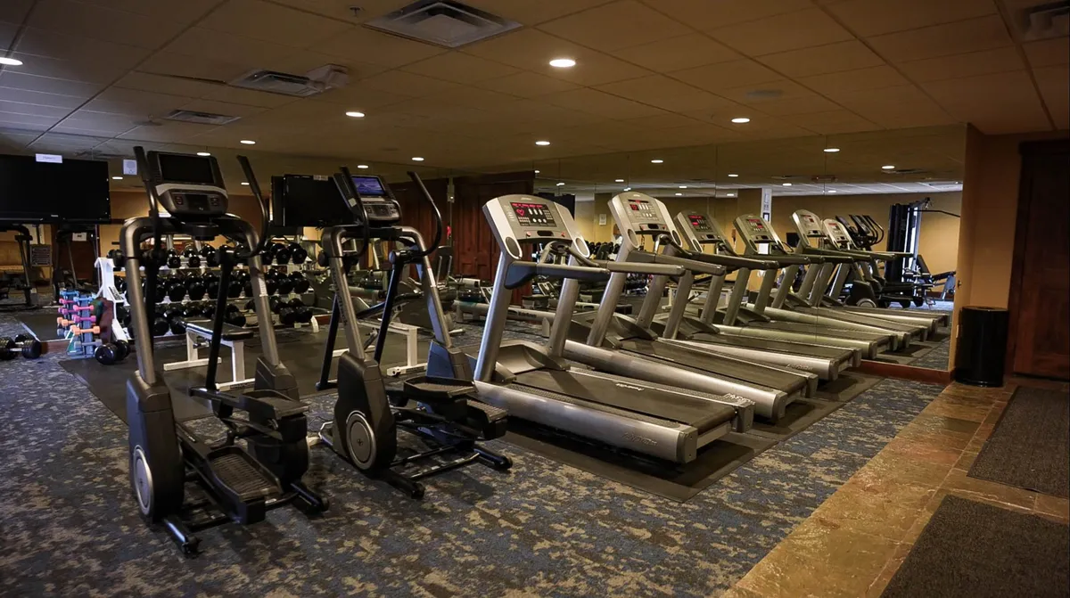 This interior image displays a modern fitness center equipped with treadmills, ellipticals, and weightlifting equipment. The space is bright and organized, encouraging guests to pursue their wellness routines.
