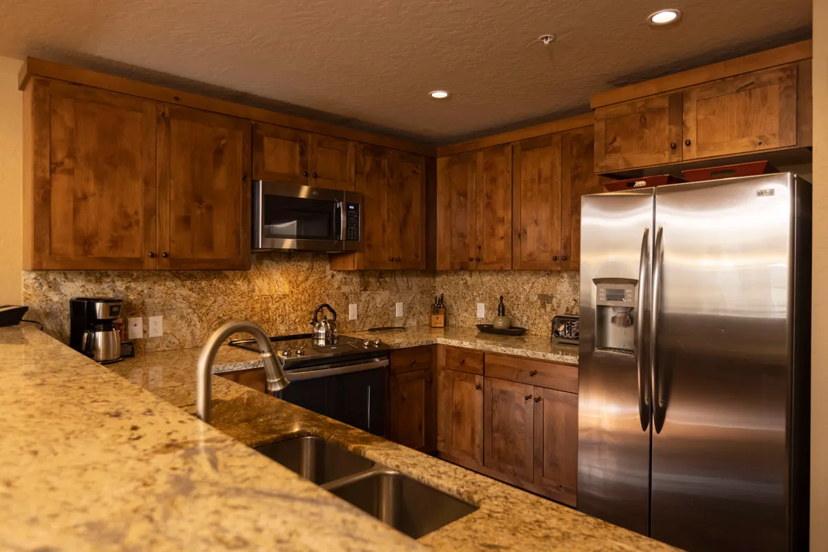 This image highlights the gourmet kitchen, featuring elegant granite countertops, modern stainless steel appliances, and warm wood cabinetry. The inviting layout encourages socializing and cooking together, capturing the essence of a chef's domain. Natural light bathes the space, enhancing its cozy atmosphere.