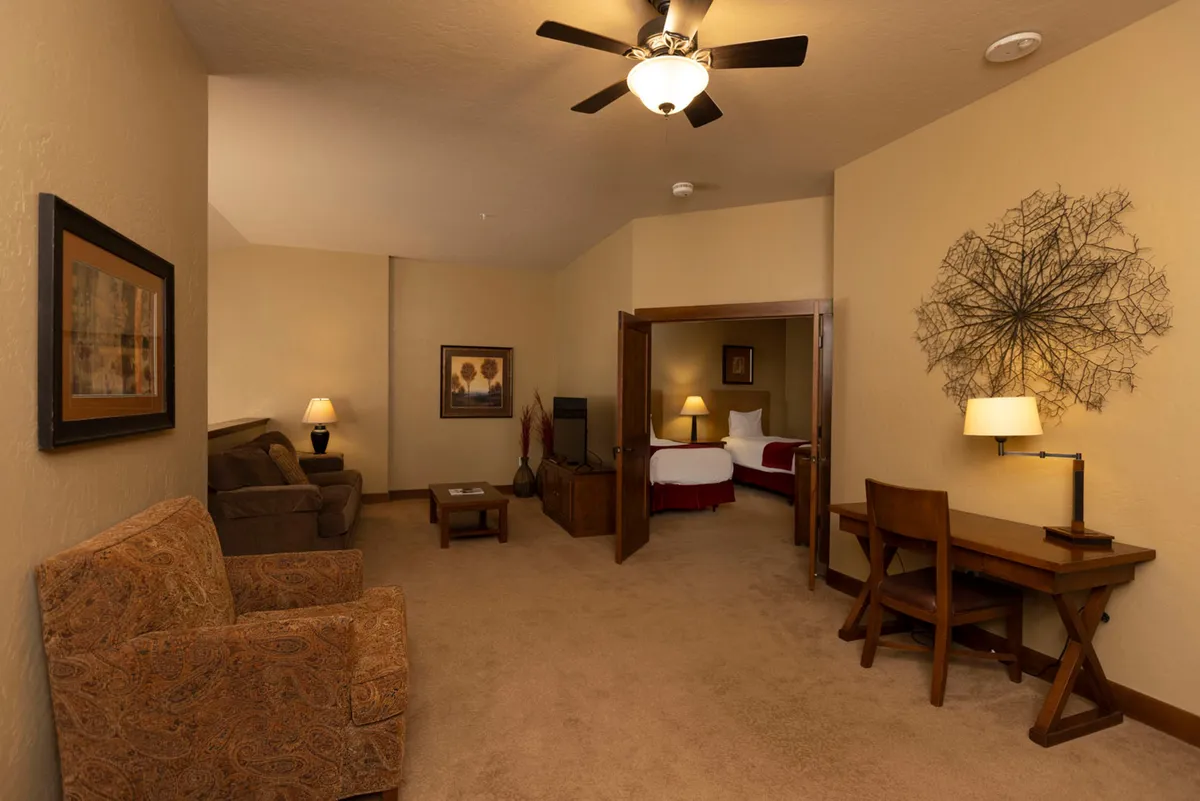A loft or secondary retreat space with comfortable seating, a functional desk with a lamp, decorative wall art, and a visible room entrance. The area feels versatile, welcoming, and tailored for both relaxation and quiet activities.